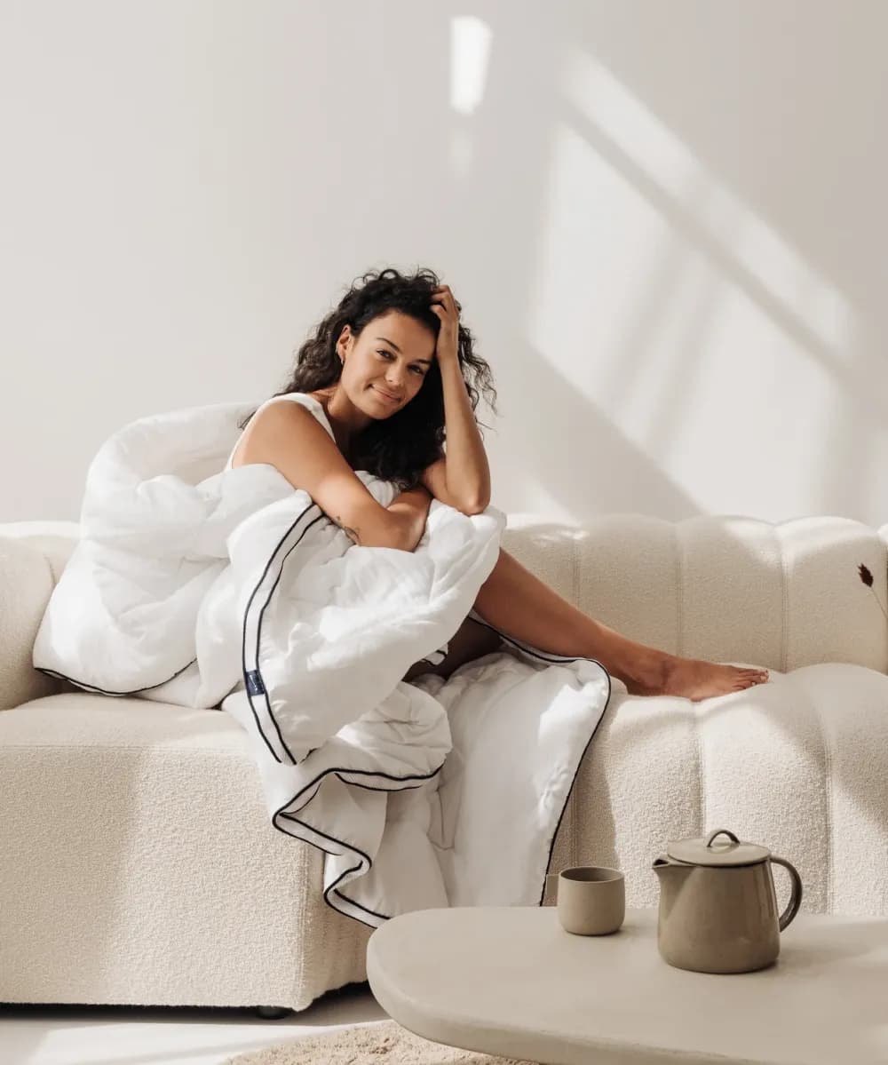Woman sitting on a sofa wrapped in a blanket